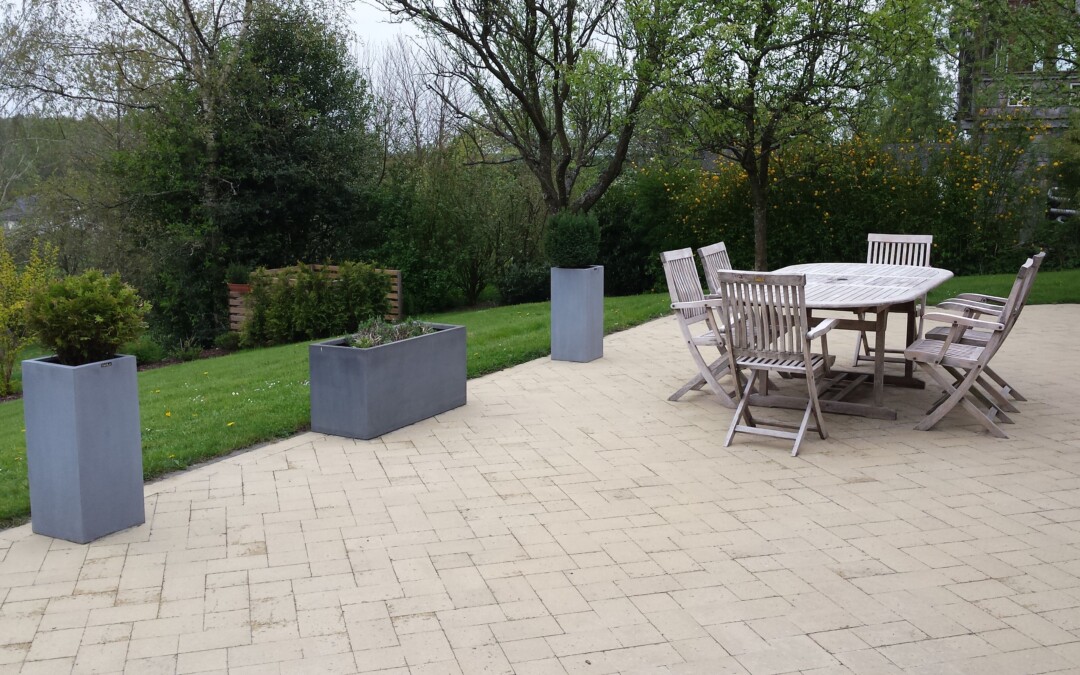 Une terrasse en pavés de béton gris, aménagée avec une table et des chaises