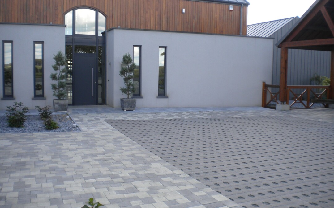 Entrée en pavés en béton devant une maison moderne avec des pots d'arbres