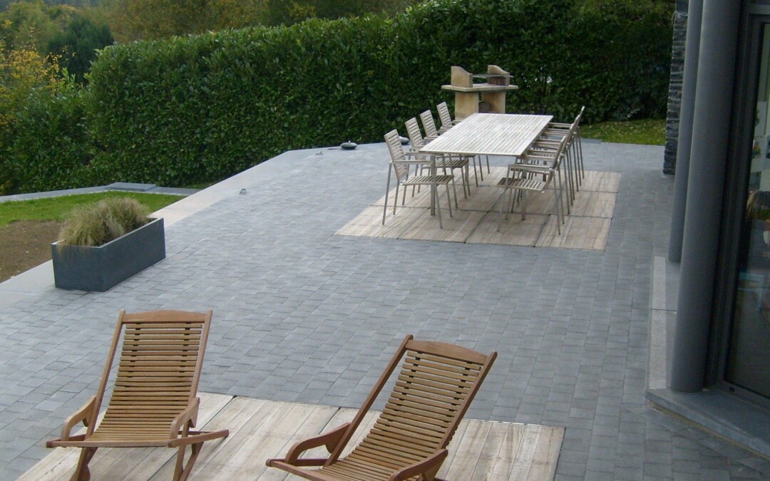 Terrasse en pavés de béton gris, aménagée avec une table et des chaises