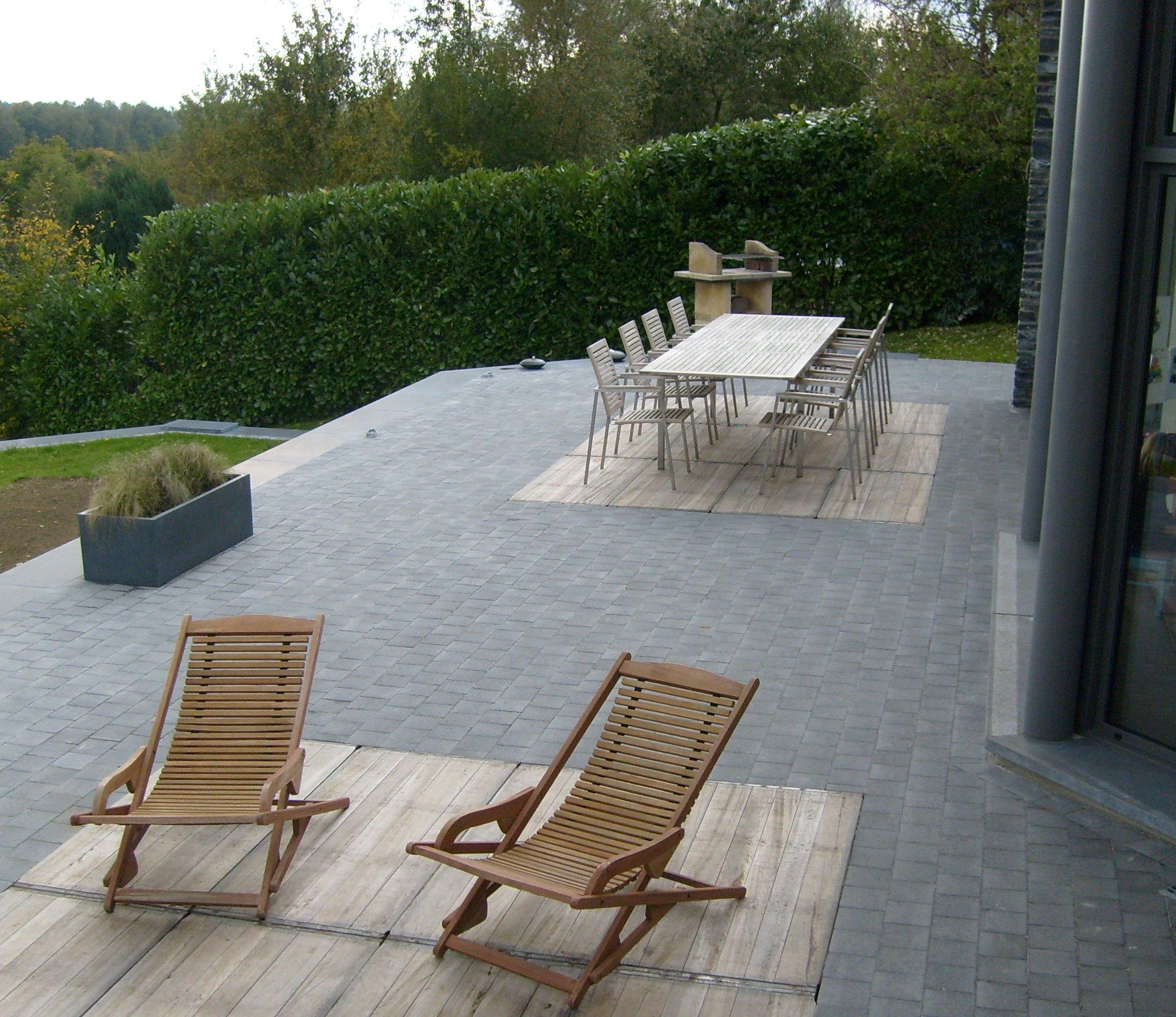 Terrasse en pavés de béton gris, aménagée avec une table et des chaises